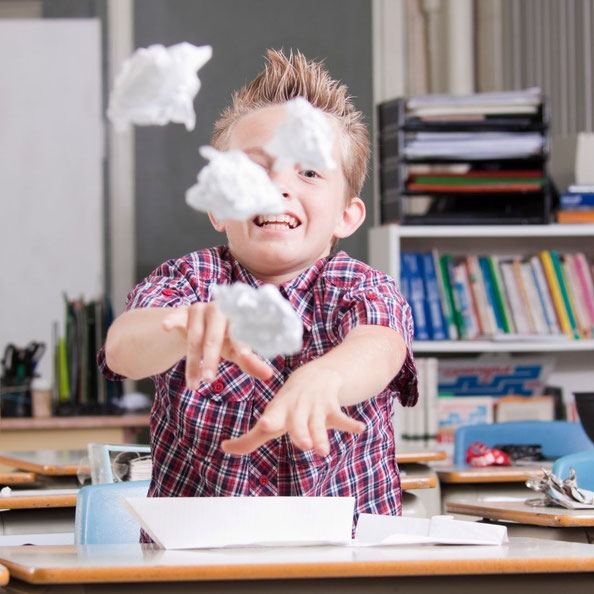 Kind wirft Papierbälle im Schulzimmer