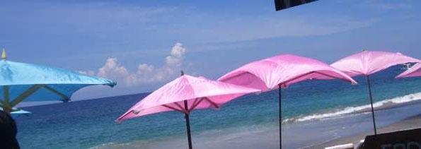 Sonnenschirme in pink und hellblau am Strand