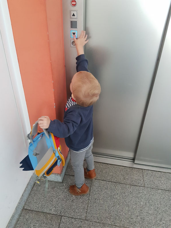 Kleinkind ruft den Fahrstuhl in Kita während der Eingewöhnungsphase.
