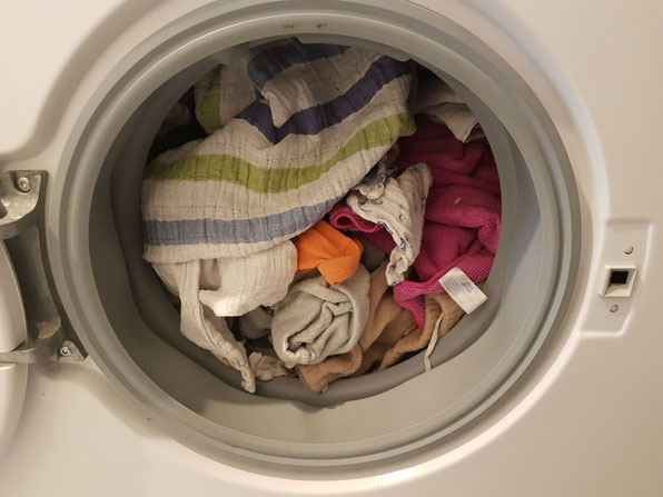 Mit Mullwindeln und Wäsche gefüllte Waschtrommel als Symbolbild für Windelfrei-Erfahrungsbericht.