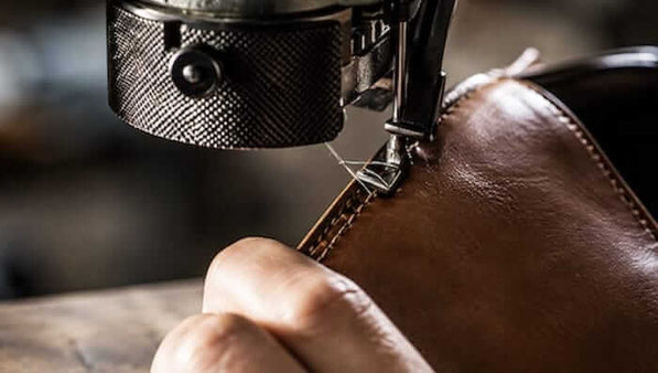 Schuhmacher repariert Barfußschuh an Nähmaschine