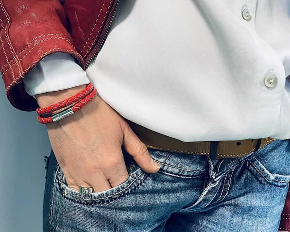 Am rechten Handgelenk einer Frau befindet sich ein doppeltes rotes Lederarmband