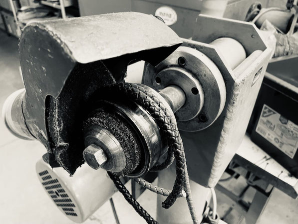 Stränge von geflochtenem Leder hängen über eine Maschine zum Flechten