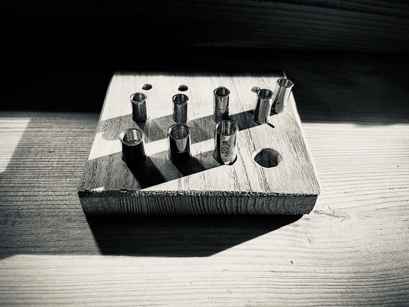 Auf einem viereckigen Holzklotz mit Löchern sind Edelstahl Magnetverschlüsse für Armbänder gesteckt