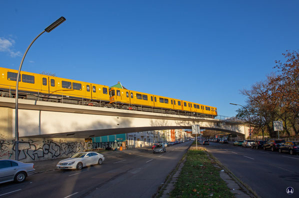 Ein F-Zug in Orange-gelb hat die Brückenmitte auf seinem Weg zum U-Bahnhof Scharnweberstraße überschritten. 