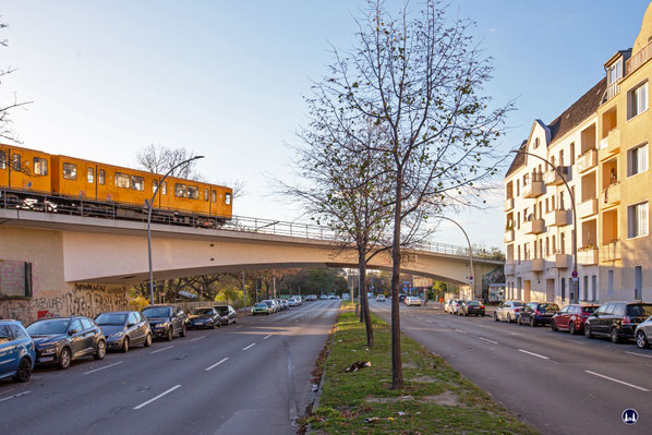 Ein Zug der Baureihe F der BVG in orange-gelb lackiert, nähert sich der Brückenmitte auf dem Weg zum Bahnhof Otisstraße. 