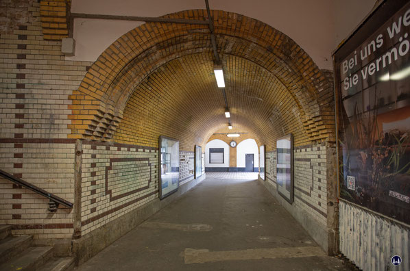 Im Hintergrund der Eingangsbereich des Bahnhofs samt den ehem. Schaltern. Die weiß - braun glasierten Ziegelsteine des gewölbten Gleistunnels sind noch weitgehend original. Man beachte zudem den kunstvoll gemauerten Gewölbeansatz. Rechts vorne hinter der 