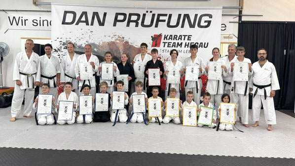 Dan Prüfung. Bild mit allen Prüflingen, allen haben eine Urkunde in der Hand und lachen, sie freuen sich die Prüfung bestanden zu haben. Gruppenbild. 
