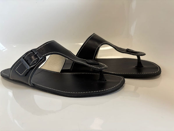 Flipflops Modell Vlop-Vlips von Senmotic. Aus pflanzlich gegerbten schwarzem Leder mit weißen Nähten und einer Metallschnalle. Die 3mm Kautschuk Sohle ist Schwarz.