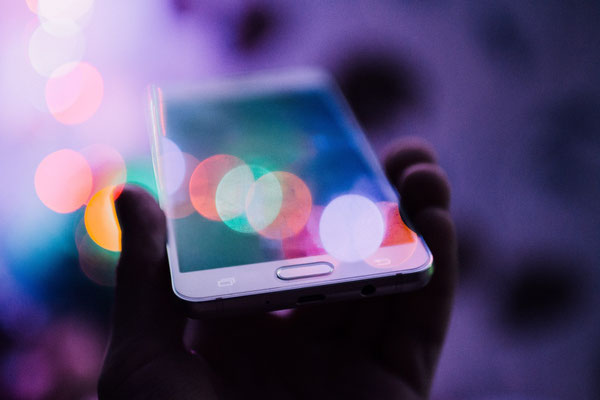 Eine Hand hält ein weißes Smartphone mit dem Display nach oben.