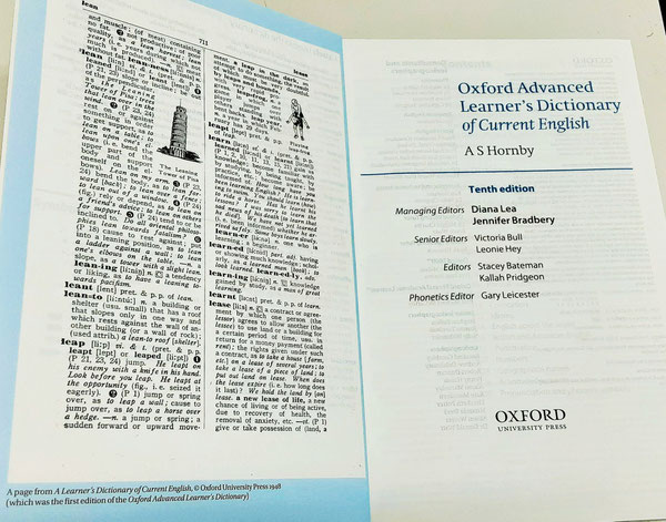 現在、世界中で使用されている『Oxford Advanced Learner's Dictionary(オックスフォード現代英英辞典)』の見開きページの題名の下に、初版の編集者 AS Hornby と大きく書かれている。左側には、1948年に英国で出版された初版の1ページが掲載されているが、その原版は日本で1942年(昭和17年)4月に出版された。(ダブルクリックすると拡大します)©Oxford University Press, ©旺文社