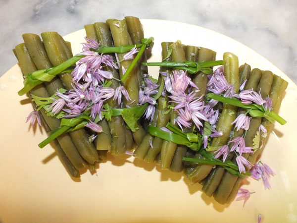 Fagots de haricots verts frais, liés de tiges de ciboulette, accompagnés de fleurs de ciboulette au délicat parfum légèrement aillé