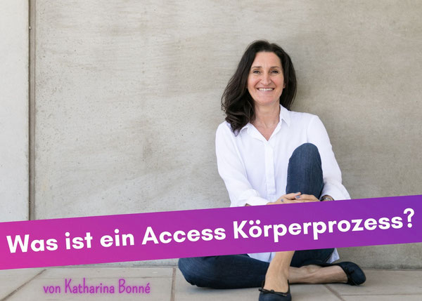Frau lehnt sitzend an eine Wand, lächelt entspannt und freudvoll