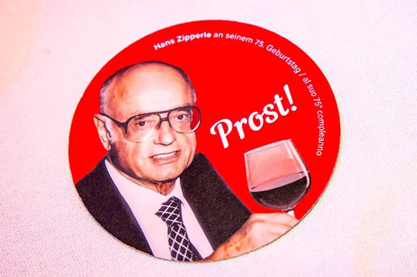 Hans Zipperle zum 75. Geburtstag mit Weinglas und „Prost!“-Anstecker – Erinnerungsfoto des Südtiroler Unternehmers aus Meran bei einer Jubiläumsfeier.