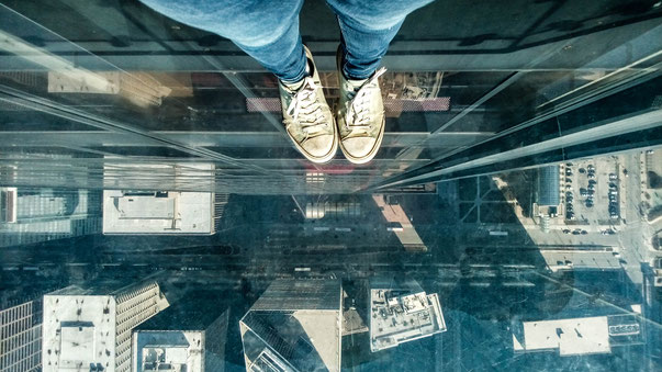 looking straight down from the willis tower skydeck standing in one of the ledges looking at chicago streets and cars and buildings