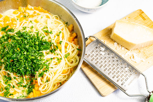 Die Pasta wird mit der Sauce, Gemüse und den frischen Kräutern im Topf vermischt und dann auf einem Teller angerichtet