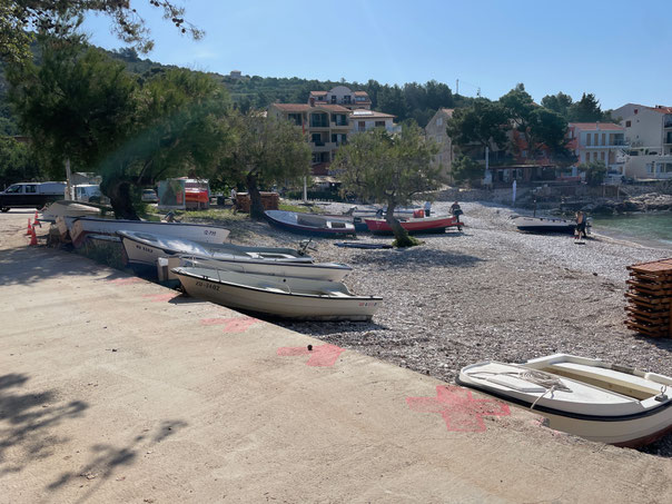 Plaza Milna - kleiner öffentlicher Kiesstrand mit Booten zwischen Camping und Dorf 