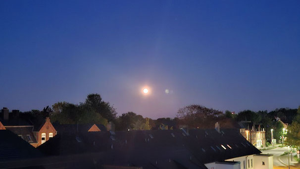 Mond scheint an klarem Himmel auf Häuser