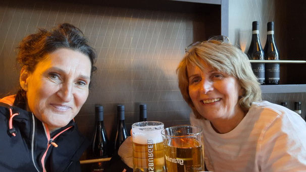 zwei Frauen an einem Tisch mit Getränk in der Hand