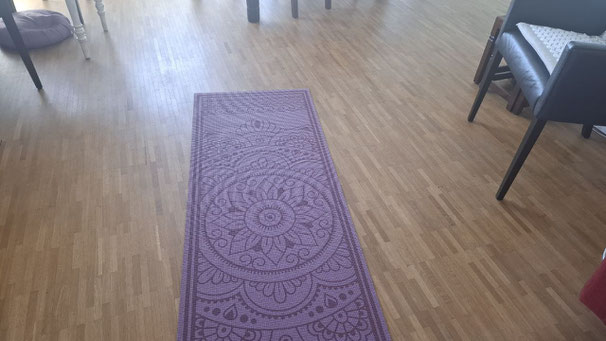 Ausgerollte Yogamatte auf Holzfußboden