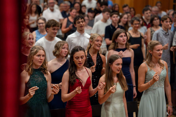 Festlich gekleidete Absolventinnen und Absolventen der Kantonsschule Schüpfheim / Gymnasium Plus während eines emotionalen Moments an der Maturafeier 2026.