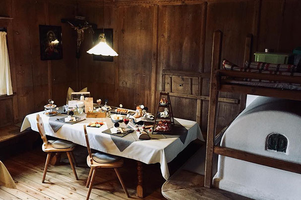 Gemütliche Bauernstube im Zuner Hof am Ritten mit gedecktem Tisch, Holzvertäfelung, traditionellem Ofen und liebevoll präsentierten Speisen