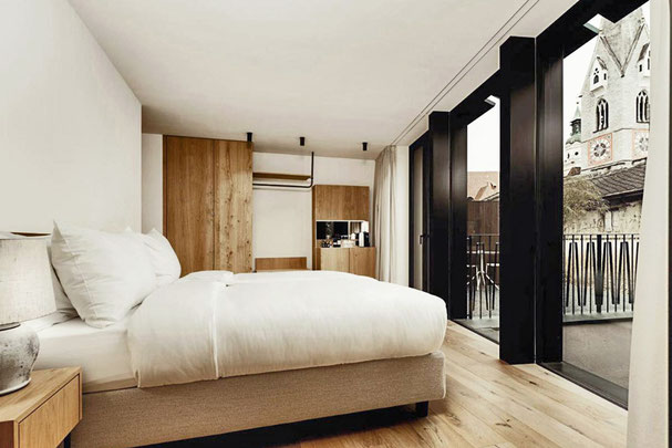 Blick in ein puristisch eingerichtetes Zimmer mit Blick auf den Brixner Dom im Adler Historic Guesthouse Hotel in Brixen in Südtirol