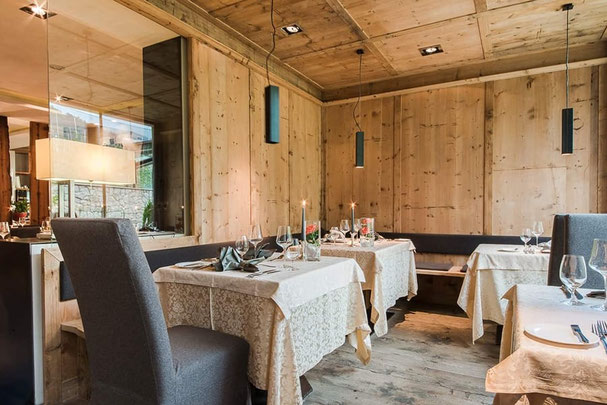 Elegantes Restaurant Kirchsteiger in Völlan mit warmem Holzinterieur, stilvoll gedeckten Tischen und gemütlicher Atmosphäre für feine Gourmetabende in Südtirol.