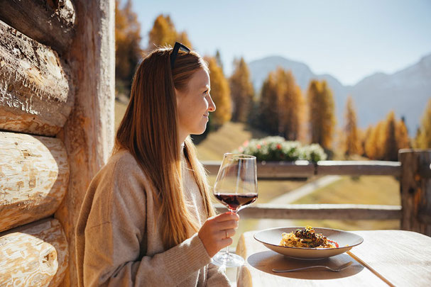 Munts dl altonn in Alta Badia: ospite gusta vino e piatti autunnali in rifugio con vista sui boschi colorati e sulle Dolomiti.
