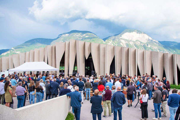 Feier zum 125-jährigen Bestehen der Kellerei Kurtatsch vor moderner Architektur, mit großer Menschenmenge, Zelten und Dolomitenkulisse im Hintergrund.