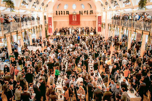 La grande sala del Kurhaus di Merano durante il Merano WineFestival con numerosi visitatori, tavoli di degustazione e un'atmosfera festosa: un evento all'insegna del piacere culinario in Alto Adige.