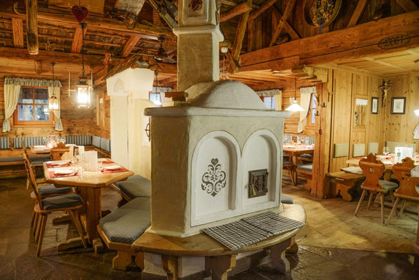Stube tradizionale del ristorante Jora Mountain Dining a San Candido con interni rustici in legno, tavoli apparecchiati, luci calde e un'accogliente atmosfera alpina.
