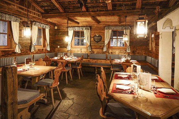 Jora Mountain Dining sul Monte Baranci a San Candido: accogliente stube altoatesina in legno antico, tavoli elegantemente apparecchiati e autentica atmosfera alpina.