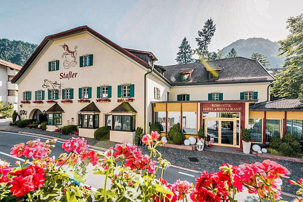 Romantikhotel Stafler in Mauls bei Sterzing mit traditioneller Fassade, blühenden Geranien im Vordergrund und Eingang zum Hotel & Restaurant