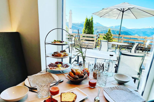 Reichhaltiges Frühstück mit regionalen Spezialitäten auf einer Etagere in Pippo's Mountain Lodge in Oberbozen mit Panoramablick auf die Südtiroler Berge