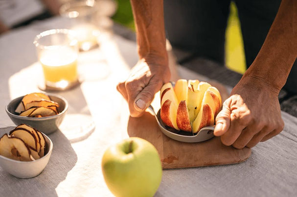  Mele fresche tagliate a mano, accanto a ciotole con fette di mela e bicchieri di succo: un momento di piacere autunnale al mercato contadino di Lagundo.