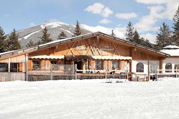 Il ristorante Jora Mountain Dining a San Candido, circondato da montagne innevate, offre un'atmosfera rustica ed è famoso per eventi esclusivi come “Pasta on the Rocks”.