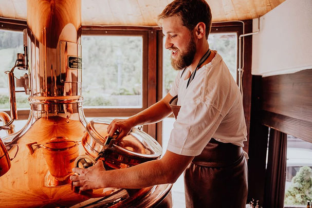 Martin vom Brauhaus Martinerhof in Passeier im Braubereich der Brauerei, im Hintergrund sind große Fenster zu sehen.