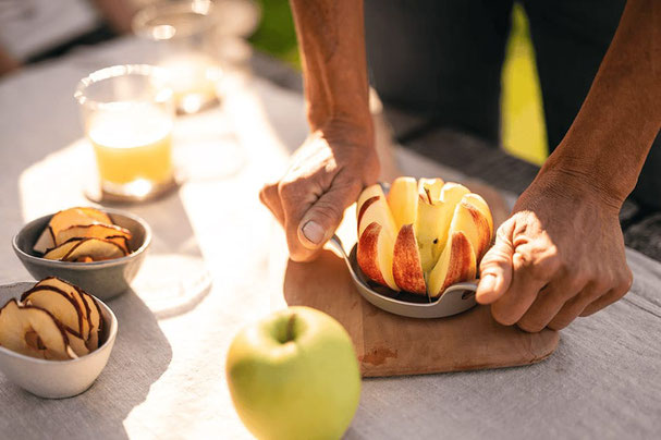 Frische Äpfel werden von Hand aufgeschnitten, daneben Schüsseln mit Apfelscheiben und Gläser mit Saft – herbstlicher Genussmoment beim Algunder Bauernmarkt.