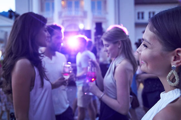 Menschen genießen einen Sommerabend mit Getränken und Musik in Meran bei entspannter Atmosphäre und stimmungsvollem Licht.