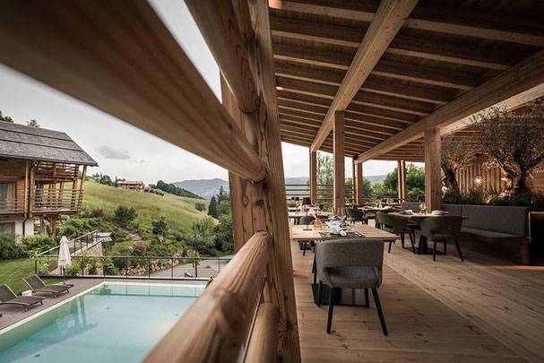 Sul lato sinistro c'è una bella e luminosa sala da pranzo con tettoia, belle sedie e tavoli scuri e sul lato sinistro una bella piscina all'aperto con una vista molto bella su prati e montagne