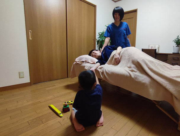 子育て中の女性が施術を受けている横で子どもが遊んでいる様子（犬山わらべ整体院）
