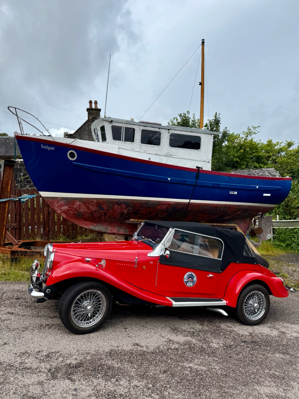 Spartan roadster in front of a boat