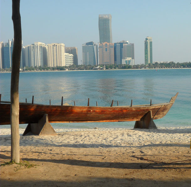 spiaggia di Dubai con piroga tipica in primo piano e grattacieli all'orizzonte