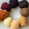 Glatte, fest verzwirnte Merino-Haargarne: Beginnend oben mittig im Uhrzeigersinn: Schwarzbraun, Schokobraun, Hellbraun (nicht im Bild, s. nächstes Foto), Dunkelblond, Goldblond 1, Goldblond 2 (nur kleine Reste), Hellblond, Kupfer, Rotbraun
