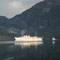 Die Morgensonne scheint auf ein Schiff im Geirangerfjord