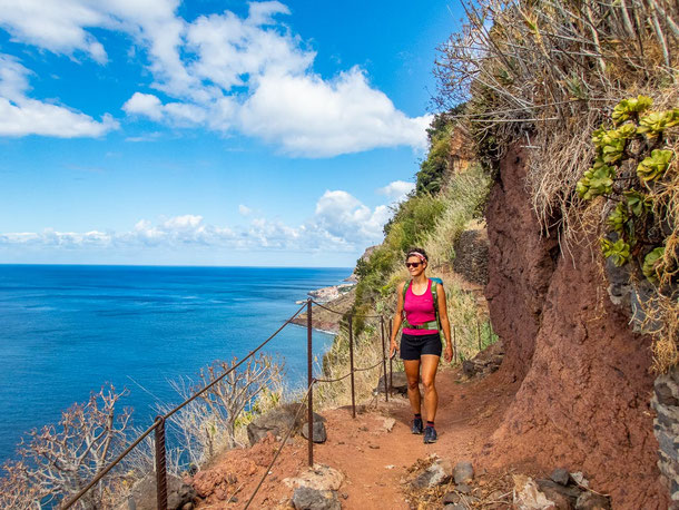 Eine Wanderin auf Madeira auf einem idyllischen Küstenpfad oberhalb des Meeres.