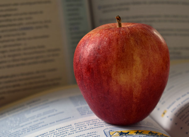 roter Apfel, aufgeschlagene Schulbücher, positive Lernumgebung