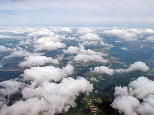 Aus dem Fenster eines Flugzeugs sieht man über und durch die Wolken, während man auf Stuttgart zufliegt, und hat einen Blick auf die Schwäbische Alb.