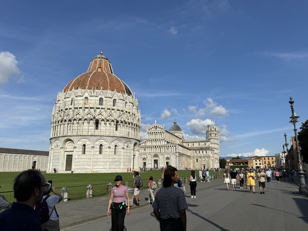 Der schiefe Turm von Pisa steht zusammen mit einer kumpelförmigen Taufkapelle (Battistero) und der Kathedrale von Pisa auf einem Gelände. 